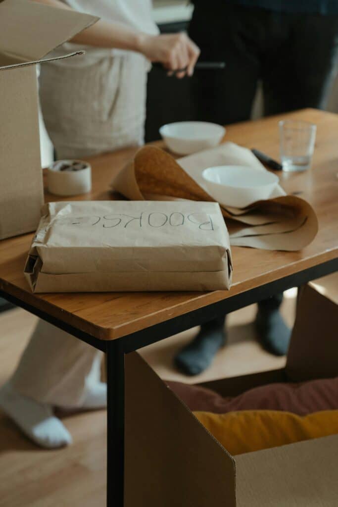 Carton marqué 'BOOKS' sur une table en bois lors d'un déménagement avec des fournitures d'emballage.